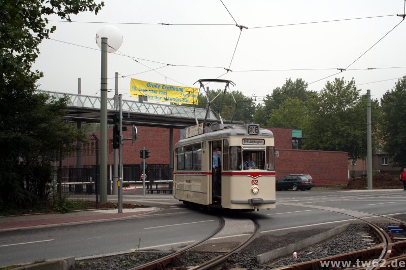 Über der Betriebshofeinfahrt hängt ein Plakat zur feierlichen Betriebshoferöffnung. Noch ahnt niemand, dass an diesem Tag 75.000 Besucher kommen werden. Das Wetter wurde auch besser, als es noch am Tag dieses Fotos war. TW 62 fährt wieder zum Buddenbergplatz.