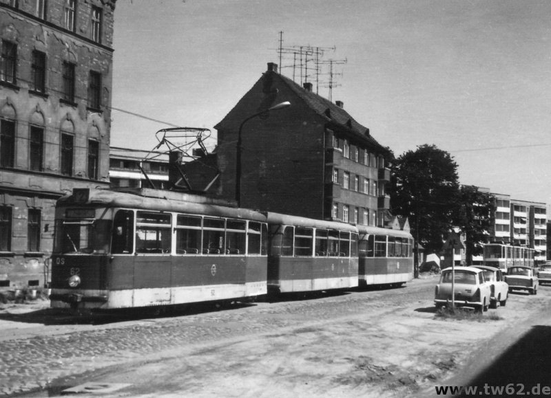 TW 62 auf der Berliner Strae ziemlich genau zwischen der Kreuzung Schweriner Strae und der Ausweiche Strbitzer Strae im Hintergrund, wo eine der ersten KT4D-Traktionen
unterwegs ist. Etwa dort befindet sich heute die Haltestelle Strbitzer Weg. Diese Ausweichstelle wurde spter bis ber die Schweriner Strae hinaus (also nach links im Bild)
erweitert und diente auch als zustzliche Abstellflche fr den nahen Betriebshof Berliner Strae. Der Zustand der Berliner Strae selbst war wie auf dem Bild zu
sehen recht erbrmlich. Der Cottbuser Volksmund nannte sie demzufolge auch "Rue de Blamage". Dieser Zustand nderte sich erst mit einer grundhaften Sanierung um die
Jahre 1998/99. Die Straenbahn verkehrt nun auf besonderem Bahnkrper in Mittellage der Strae. Die Fahrzeiten der Straenbahn haben sich dennoch nicht wesentlich reduziert,
was auch an den merkwrdigen Ampelschaltungen liegt - aber das ist ein anderes Thema ...